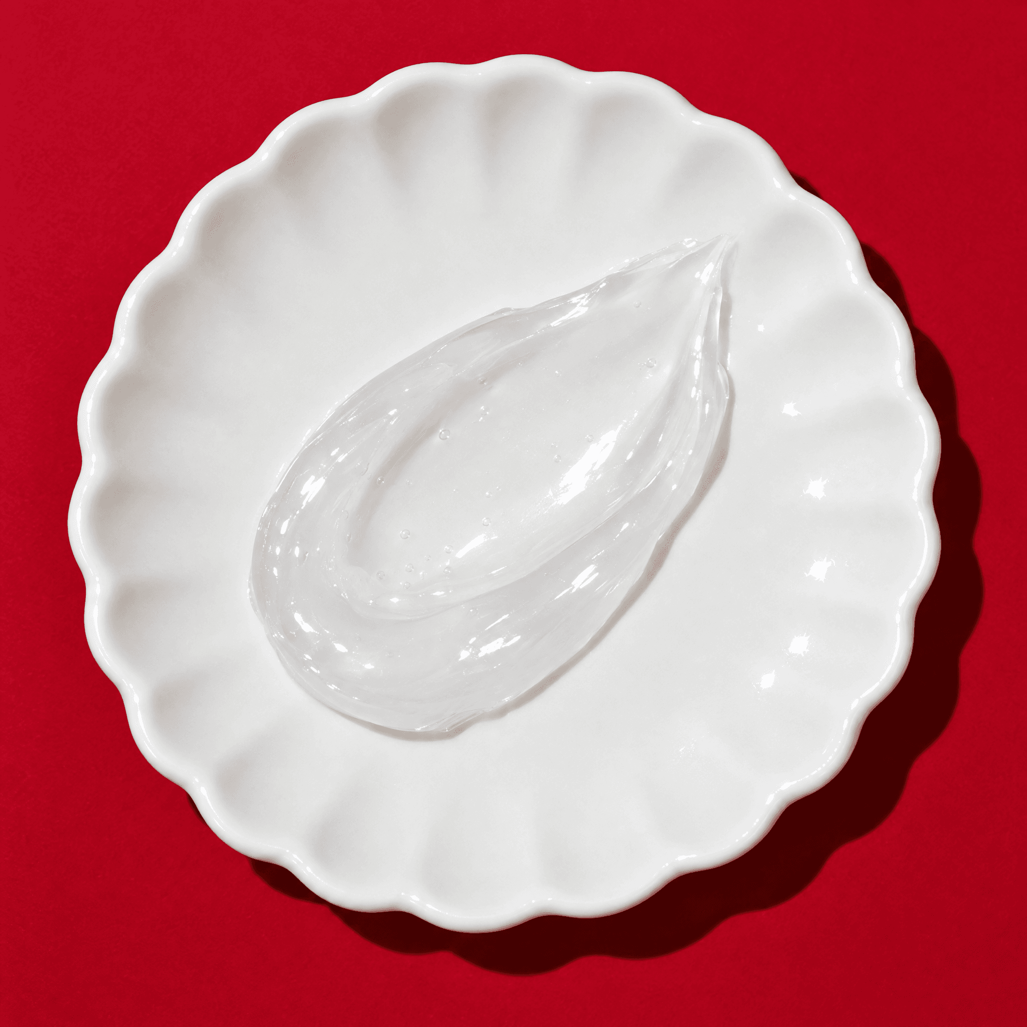 A swirl of clear gel-cream in a white scalloped dish.